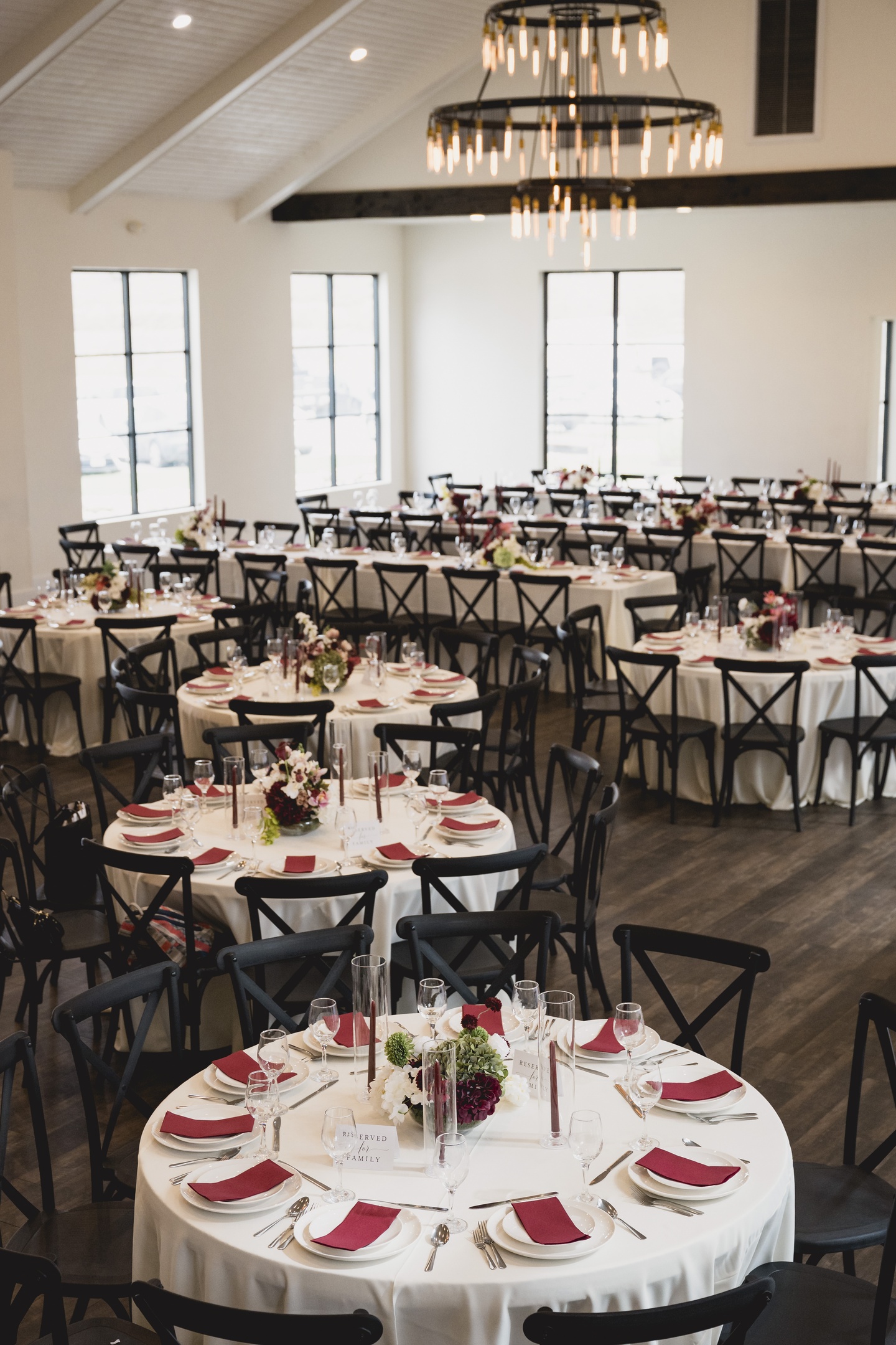 A wedding table covered with a white tablecloth, decorated with flowers, candles, glasses and cutlery.